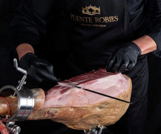 Maestro jamonero cortando un jamón ibérico Puente Robles