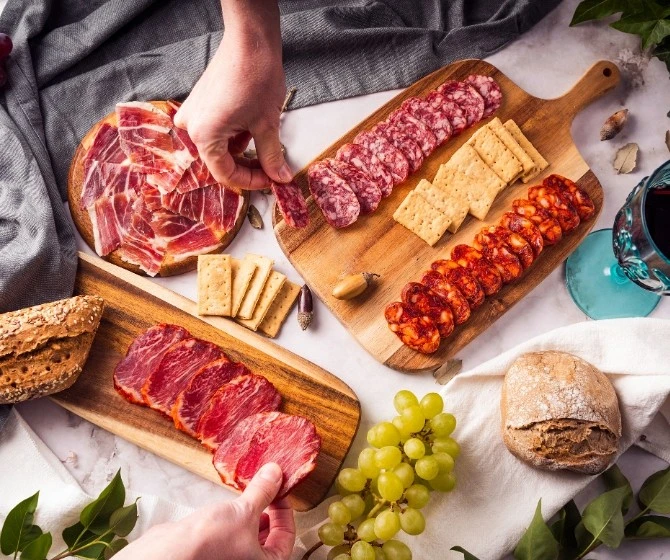 Tabla de embutidos para navidad sobre madera con frutas y pan